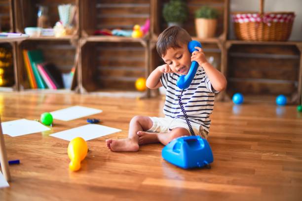 Красиво малко момче, което си играе с ретро син телефон в детска градина